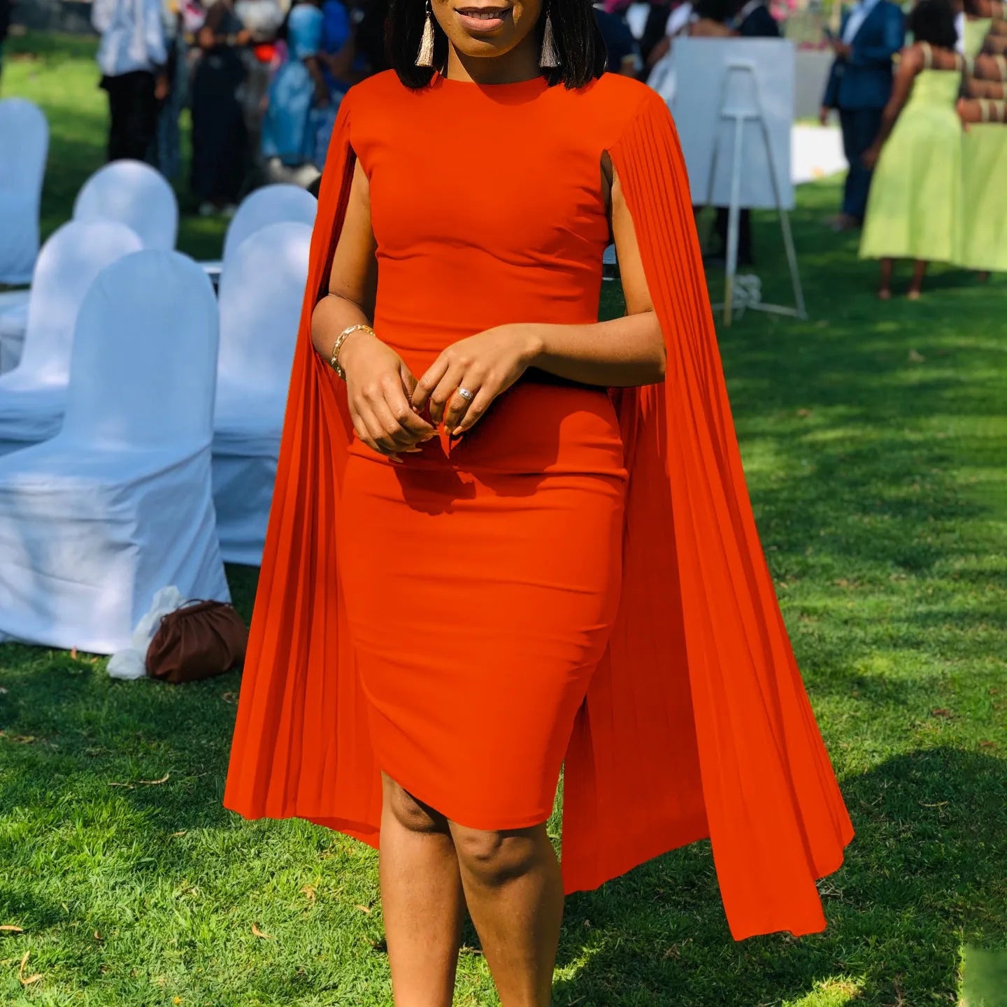 A woman wearing a long sleeve, high-waisted pleated evening gown in a formal setting.