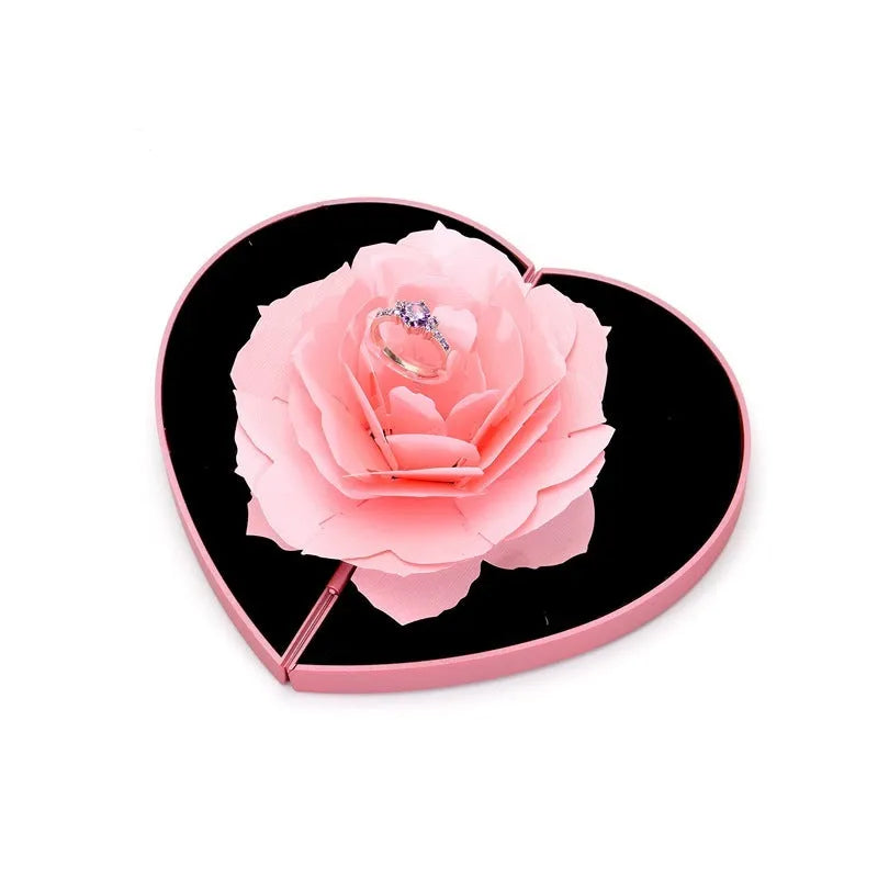 Red plastic heart-shaped rotating ring box with rose decoration inside white storage case