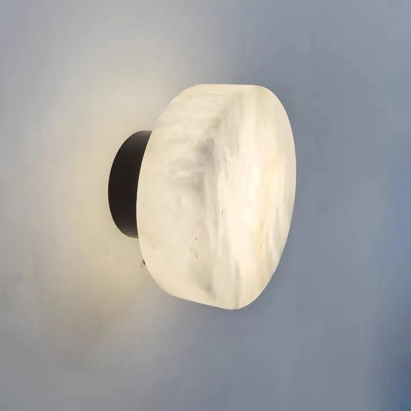 Spanish natural marble round wall lamp with warm light, 130mm diameter, black finish on a bedroom wall