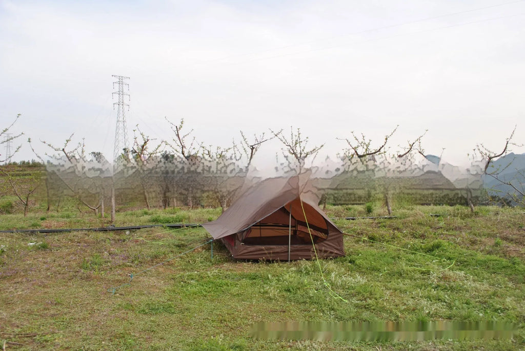 Brown ultralight A-frame hiking tent pitched with hiking poles in an outdoor setting
