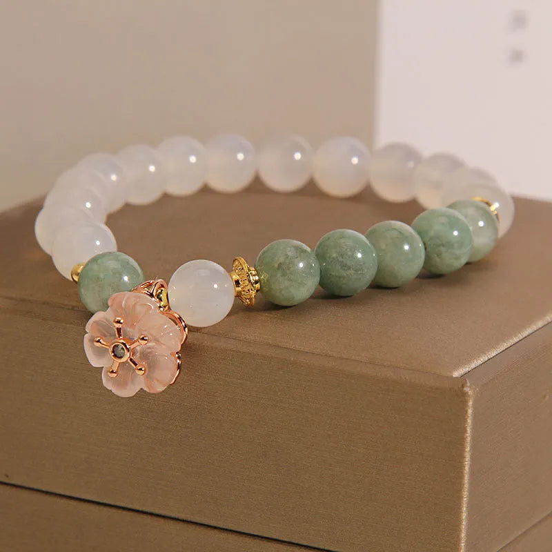 Women's white agate jade flower bracelet on a wrist, showing detailed floral carving.