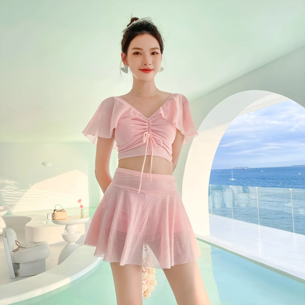 White two-piece women's swimsuit with a skirt bottom, shown alongside black and pink colour options.