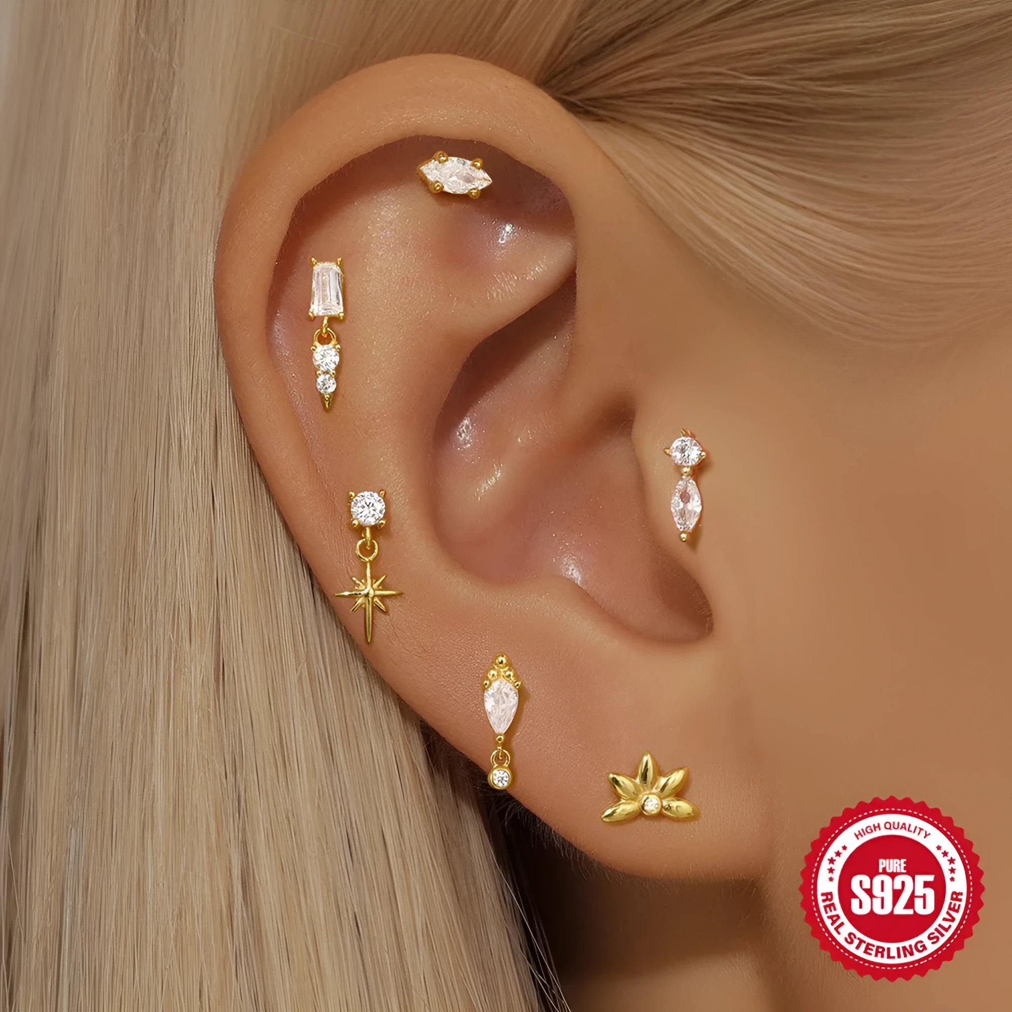 Close-up of a gold-coloured S925 sterling silver ear stud with a XINGX pattern inlay and a thin dangling tassel.
