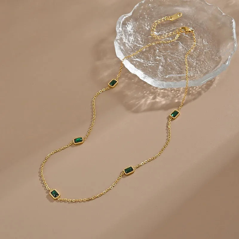 Titanium steel emerald zircon necklace and bracelet set with gold hardware and O-ring chain on a white background