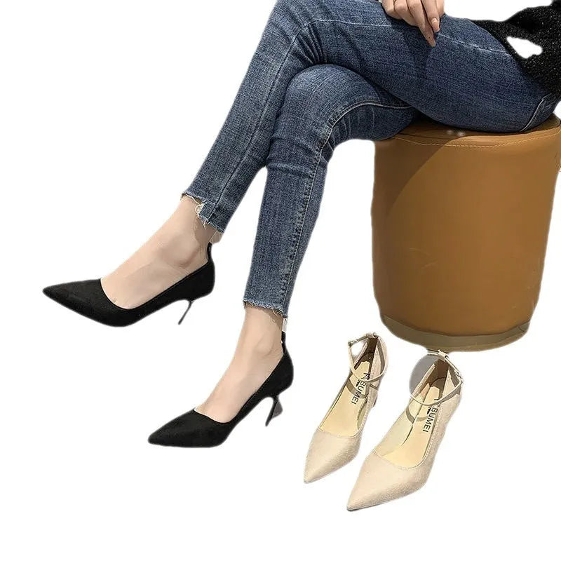 Women's black stiletto heel pumps with skull pattern and buckle detail on wooden floor