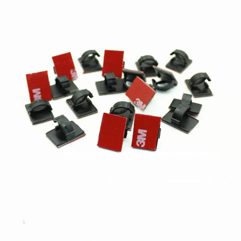 Black and white self-adhesive plastic flat cable clamps for wire organisation.