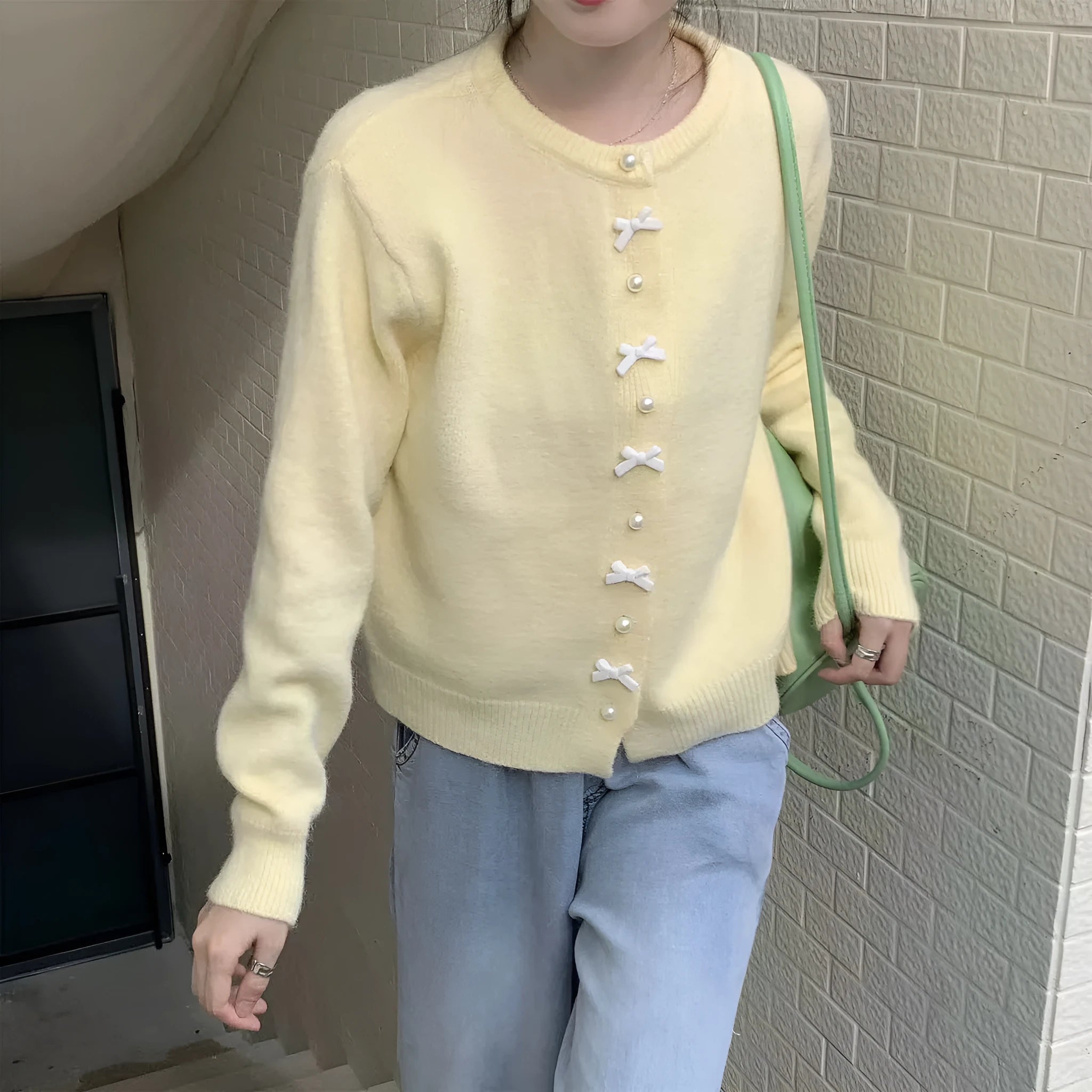 Women's solid colour cardigan sweater with bow and pearl buttons, shown in light yellow.