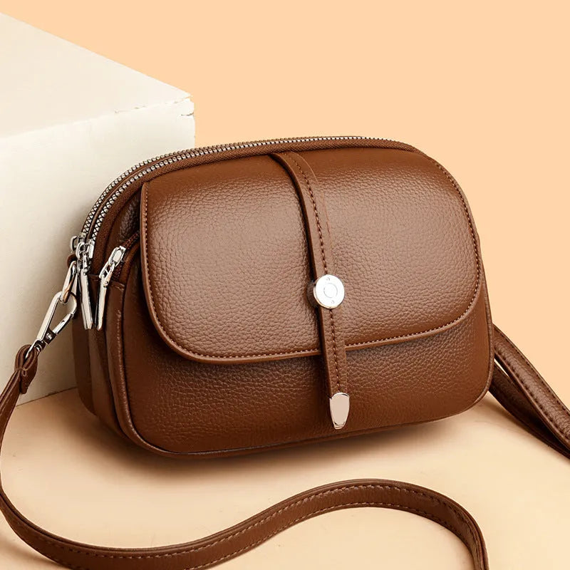 Women's oval crossbody shoulder bag in black, khaki or dark brown with visible sewing thread detail