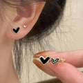 Three pairs of women's heart-shaped alloy earrings in gold, black, black and white, and pink colours