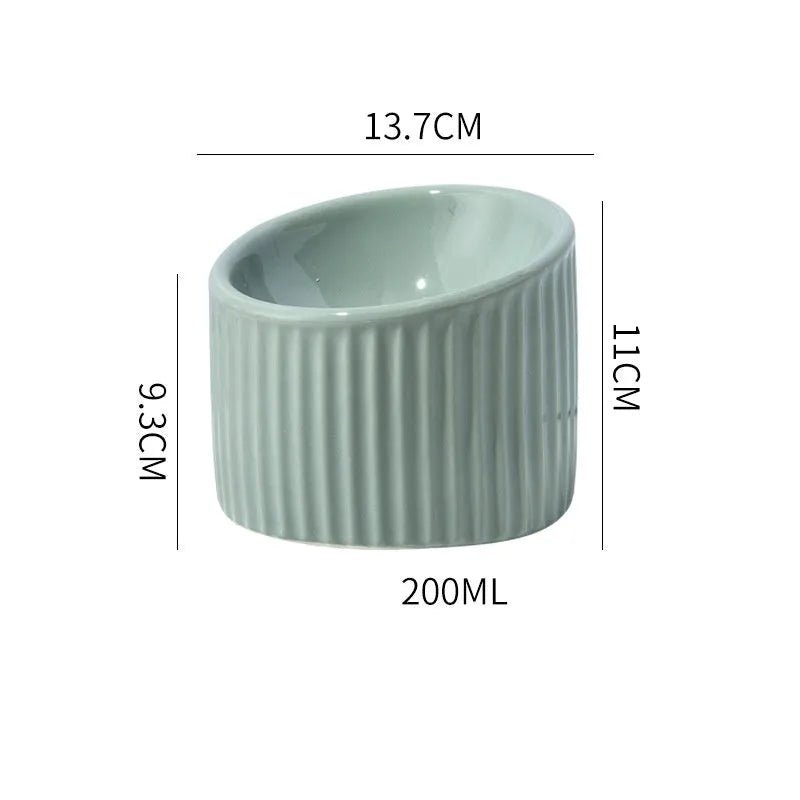 Dark green ceramic elevated cat bowl with tilted, round design on a wooden floor.