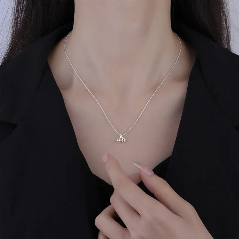 Silver cherry necklace for women with adjustable snake bone chain on a grey background.
