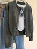 Dark grey women's button-up cardigan sweater with long sleeves on a hanger.
