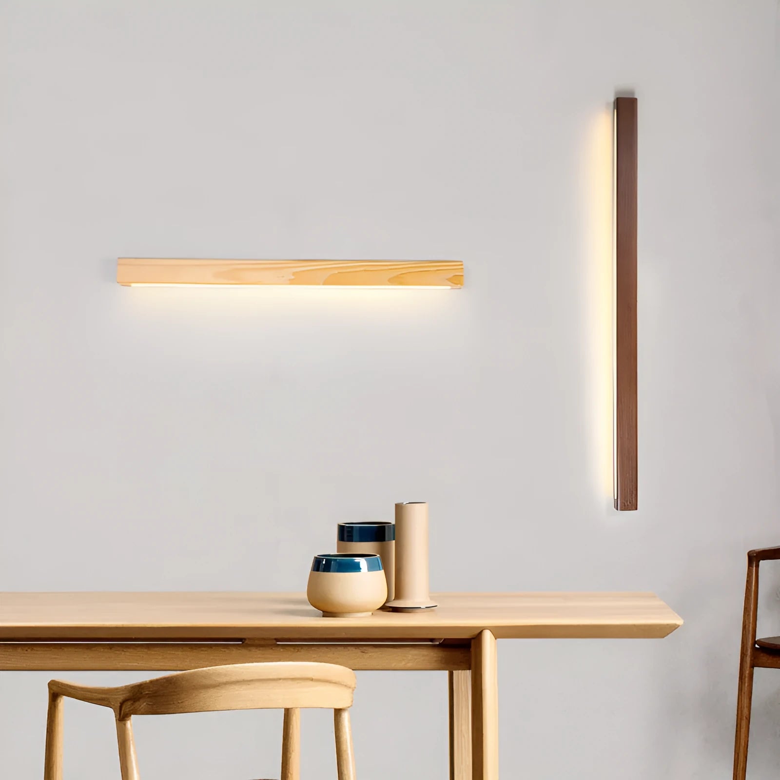 Slim, long walnut-coloured wooden strip wall lamp mounted on a plain wall.