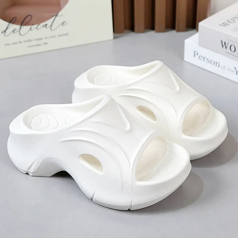 Women's white thick-soled EVA slippers with round toe on a beach background.