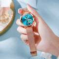 Women's fashion watch with rose alloy case, coloured dial, and stainless steel mesh strap.
