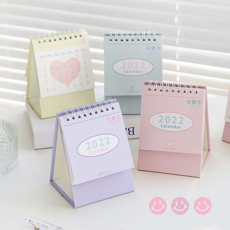 Cream coil-bound desk calendar for 2022, paper, Regular size, on a desk with month view visible