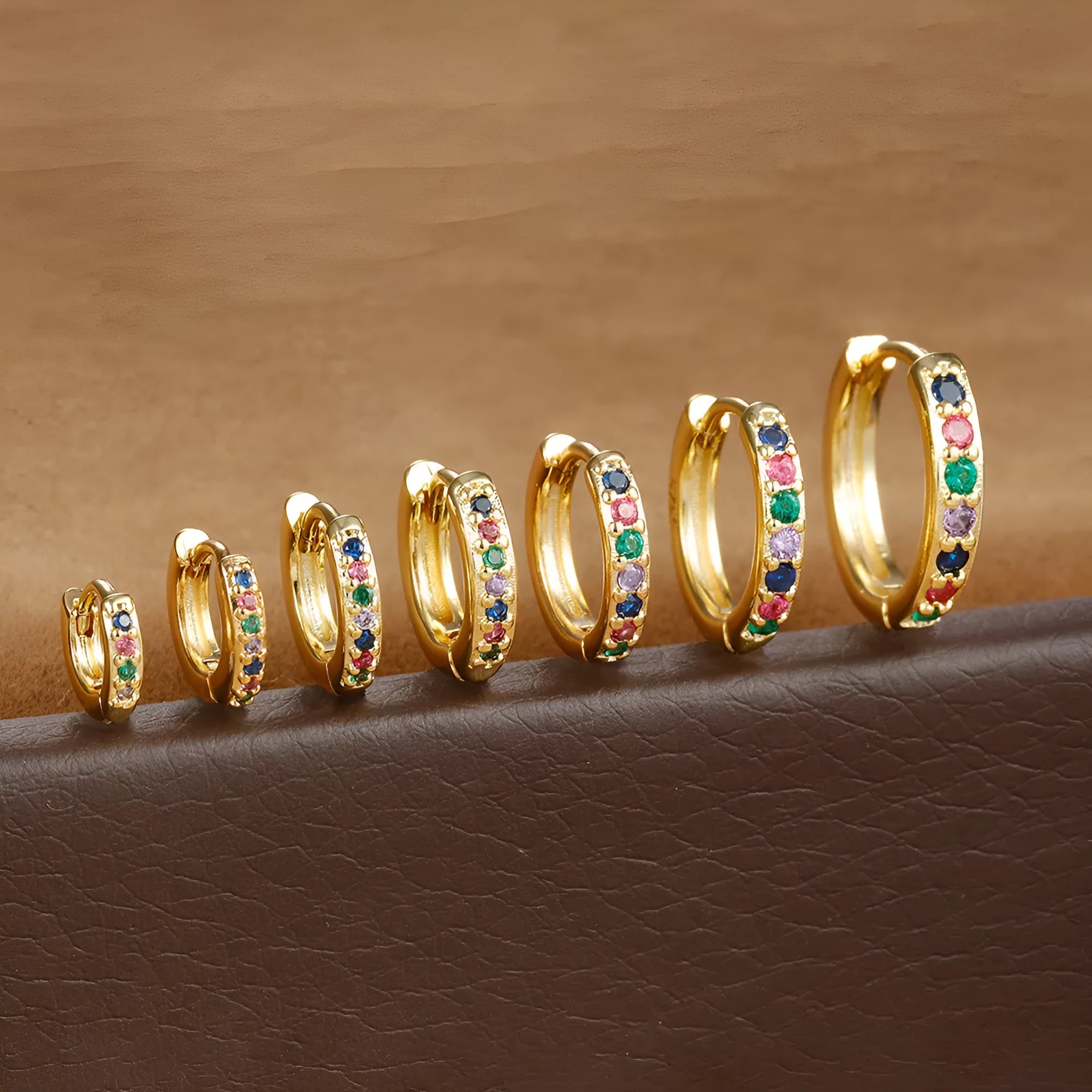 Set of three pairs of perforated circle stud earrings in gold, rose gold, and silver colours on a plain background.