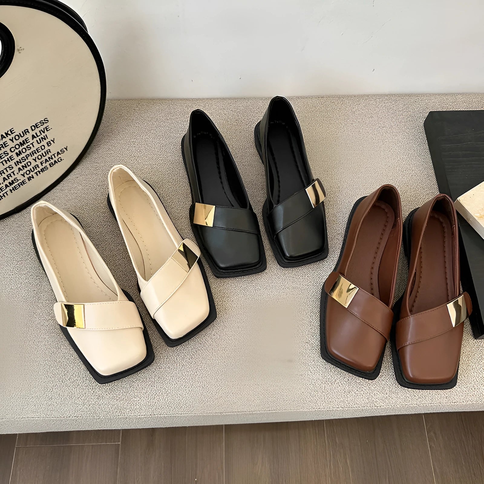 Women's beige square-toe flat shoes with a metal buckle and low rubber sole.