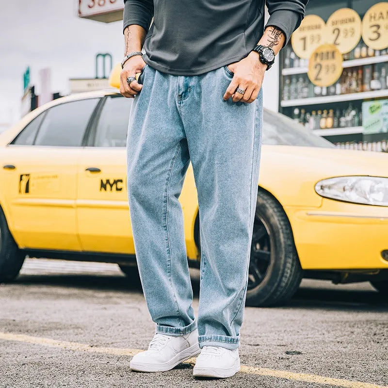 Men's dark blue loose straight-leg casual jeans on a hanger, showing mid-waist and zipper fly.