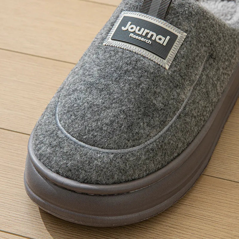 Men's grey suede slippers with a thickened sole on a wooden floor.