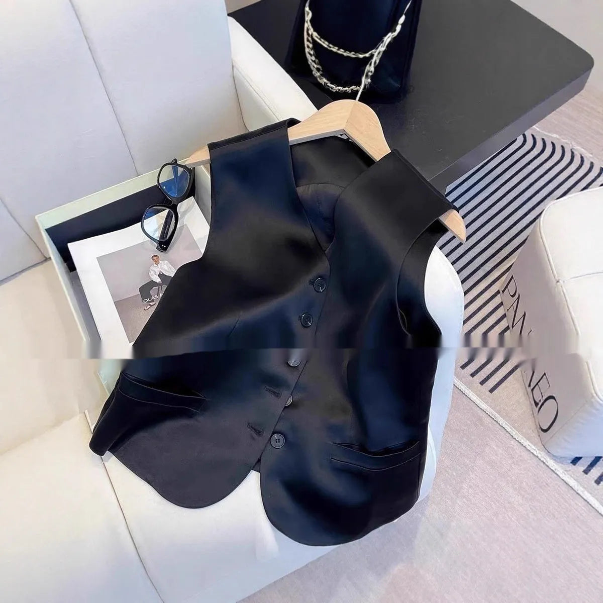 Black satin ladies sleeveless vest with V-neck and loose fit on a hanger.