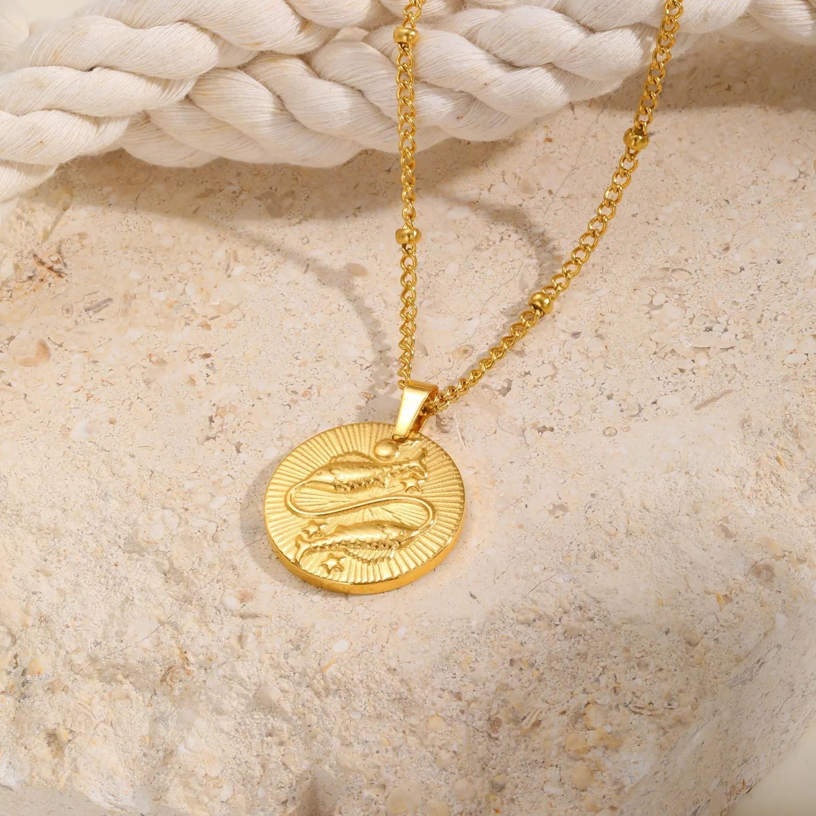 Stainless steel zodiac constellation necklace with round pendant showing embossed star signs on cross chain