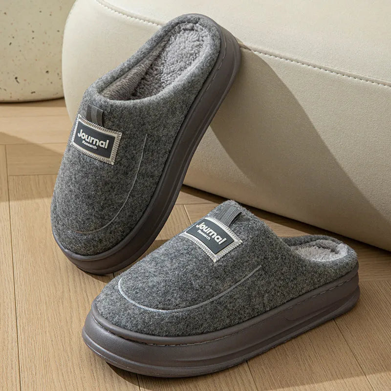 Men's grey suede slippers with a thickened sole on a wooden floor.