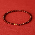 Handmade natural cinnabar koi bracelet with gold balls on a bead, showing traditional Chinese style.
