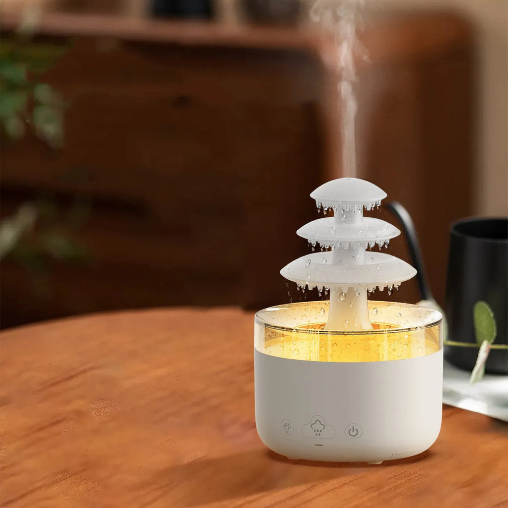 White cloud rain shape ultrasonic humidifier and essential oil diffuser with colourful LED lights on a table.