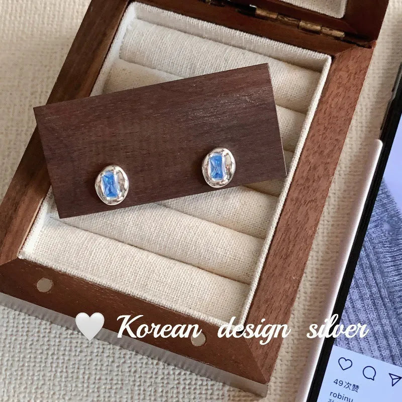 Sterling silver earrings with heart-wrapped oval blue diamond design and electroplated finish