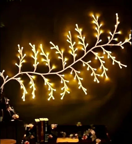 Flexible plastic LED vine garland with warm white lights shaped on a wall.