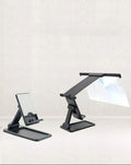 Black folding mobile phone screen amplifier with detached phone holder on a desk