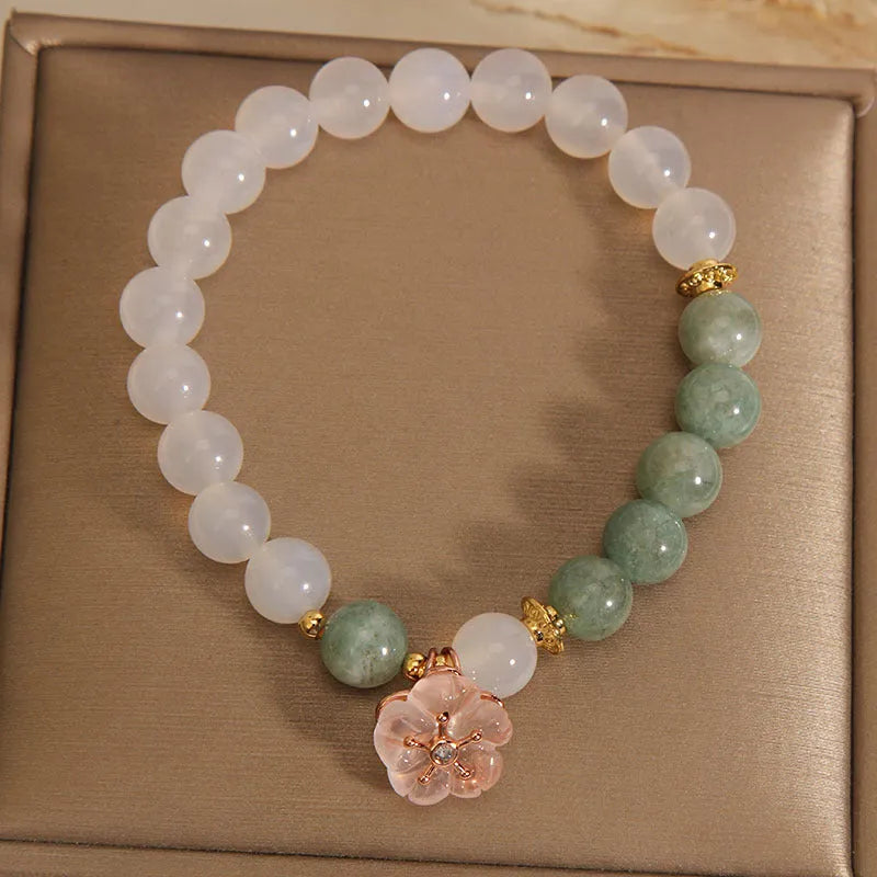 Women's white agate jade flower bracelet on a wrist, showing detailed floral carving.