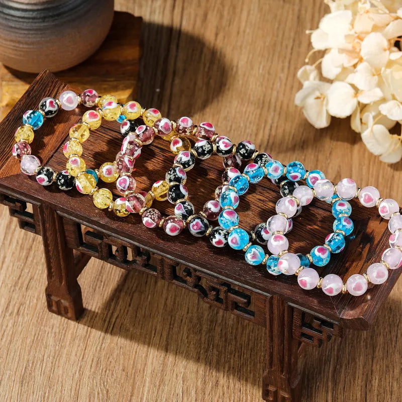 Glass bracelet with 10mm heart beads featuring ancient swallowing gold beast design in multiple colours