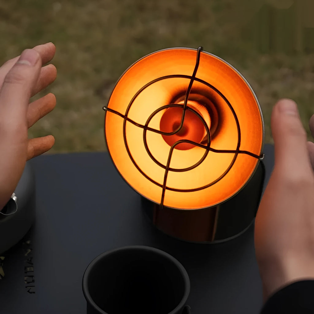 Black and orange portable outdoor gas heating stove with automatic ignition on a camping table.