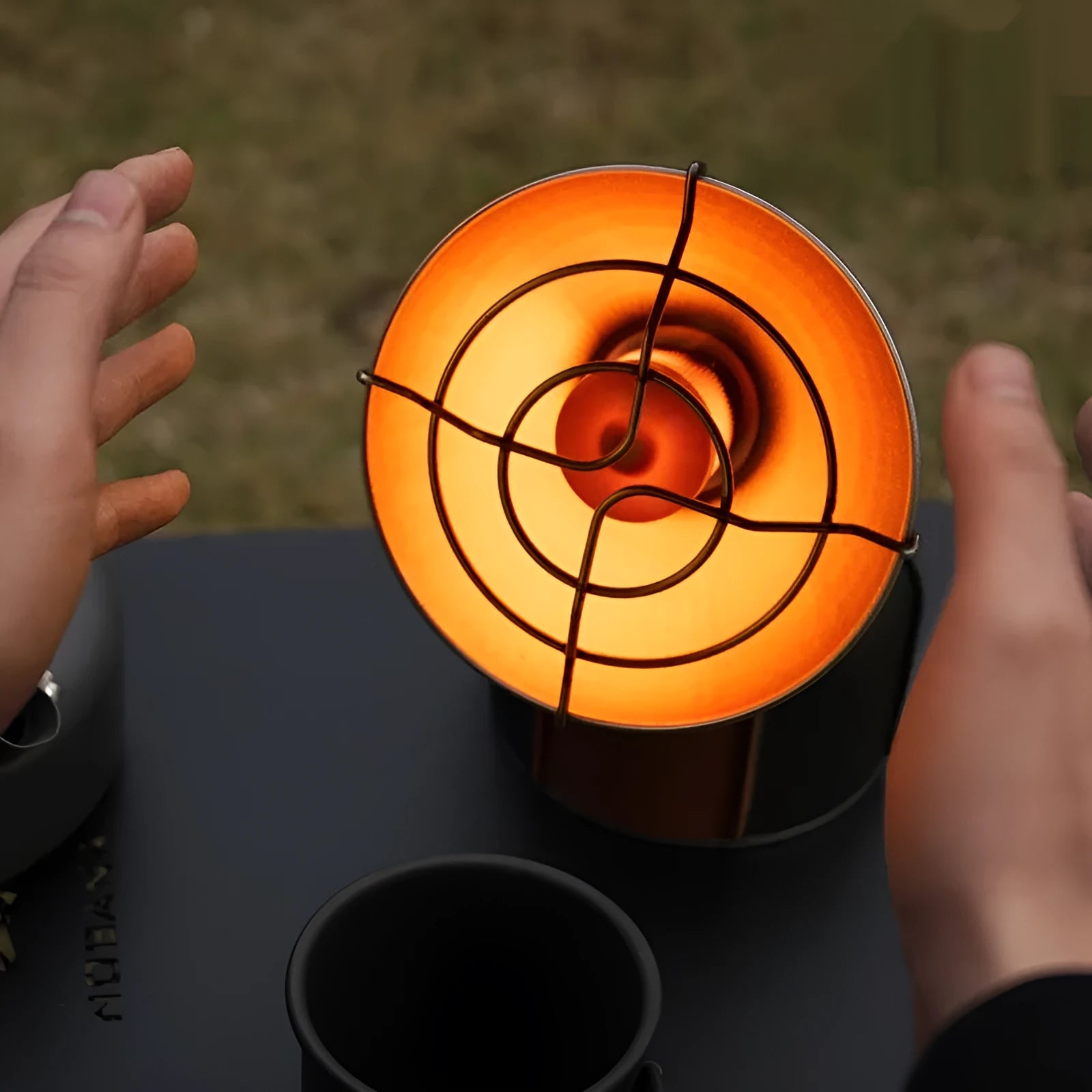 Black and orange portable outdoor gas heating stove with automatic ignition on a camping table.
