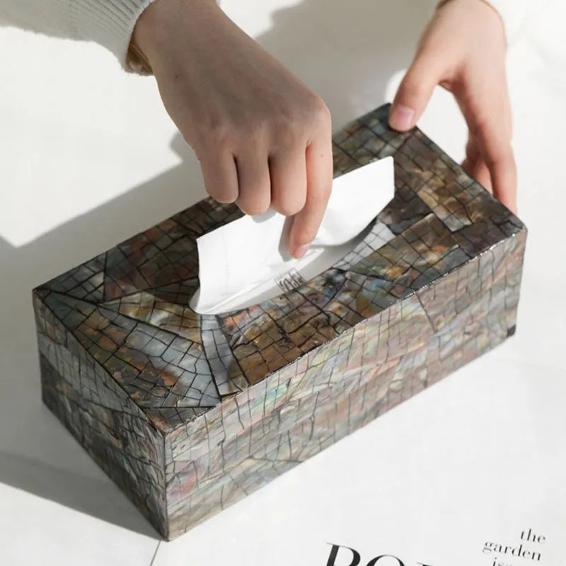 A black square natural shell storage box with a removable white internal organiser on a wooden table.