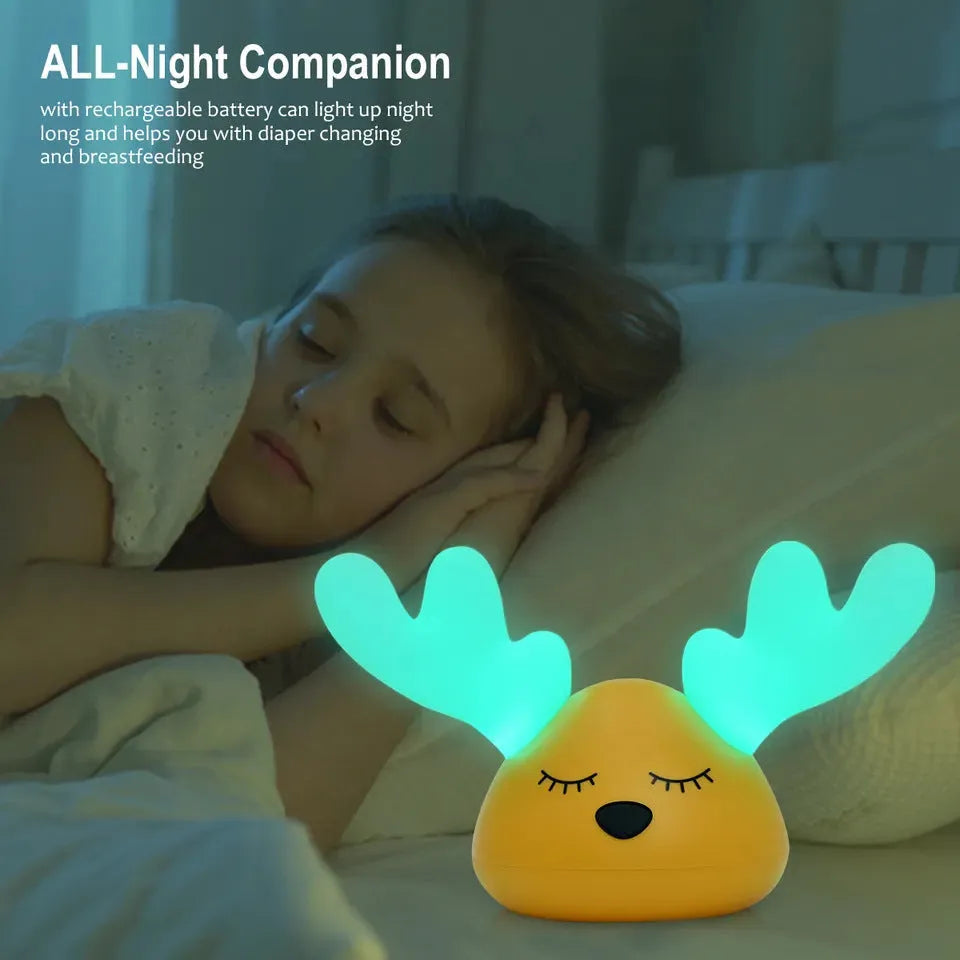 Children bedside Christmas deer night light with colour-changing LED and soft silicone shade on a table