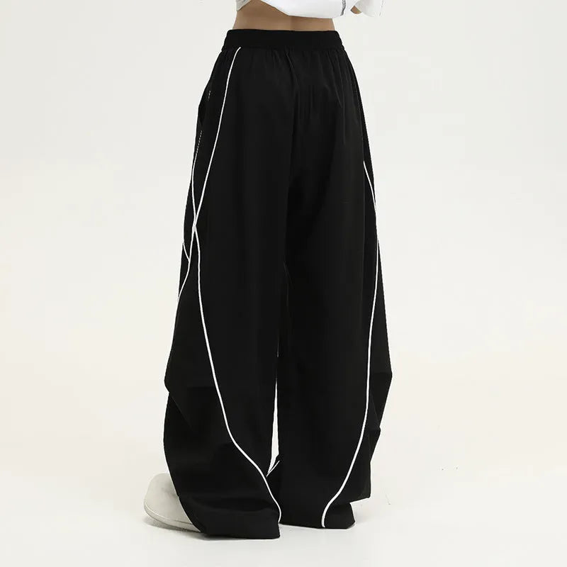 Black striped pleated wide-leg hip hop trousers laid flat, showing loose fit and mid waist.