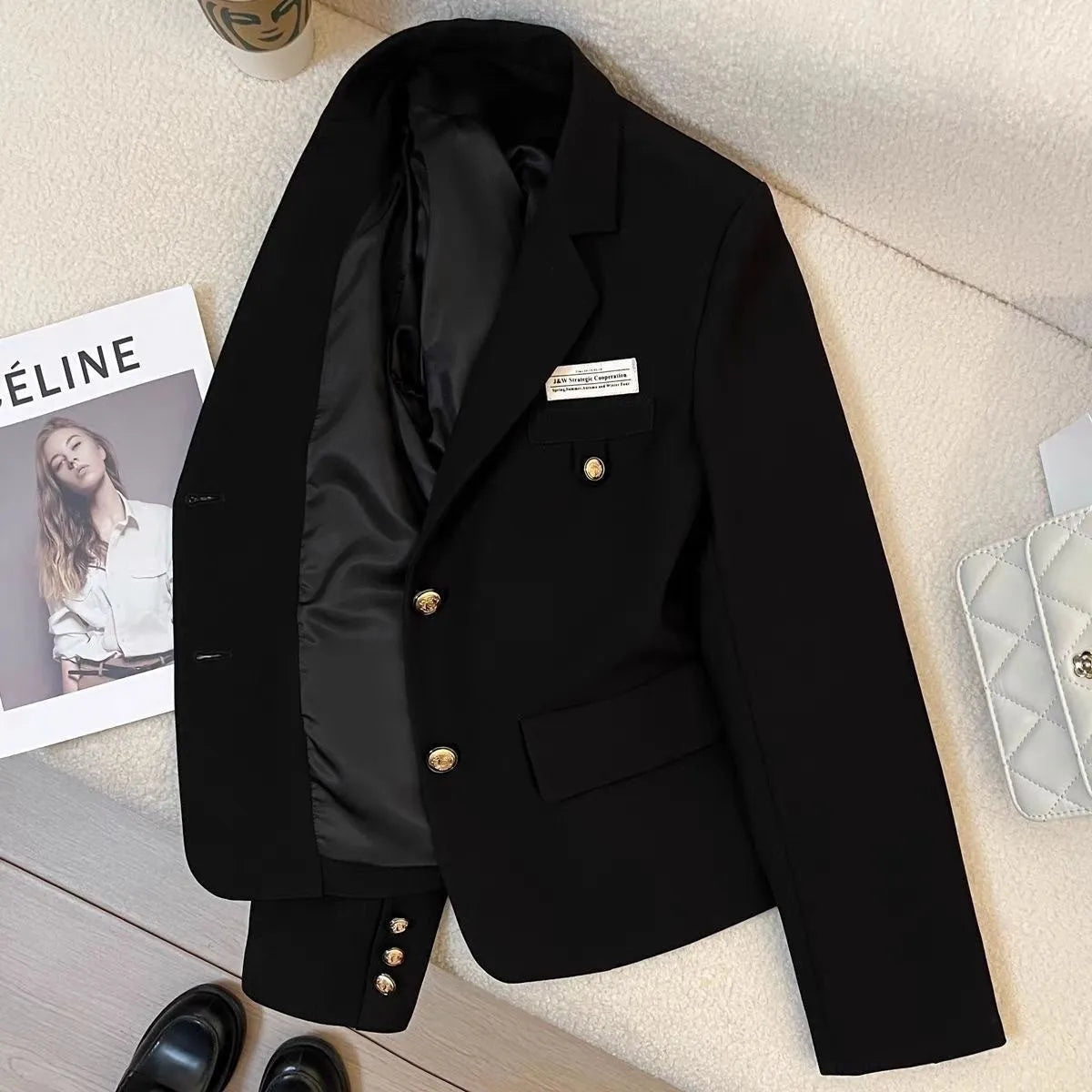 Black loose-fit women's short suit coat with long sleeves and pockets on a hanger.
