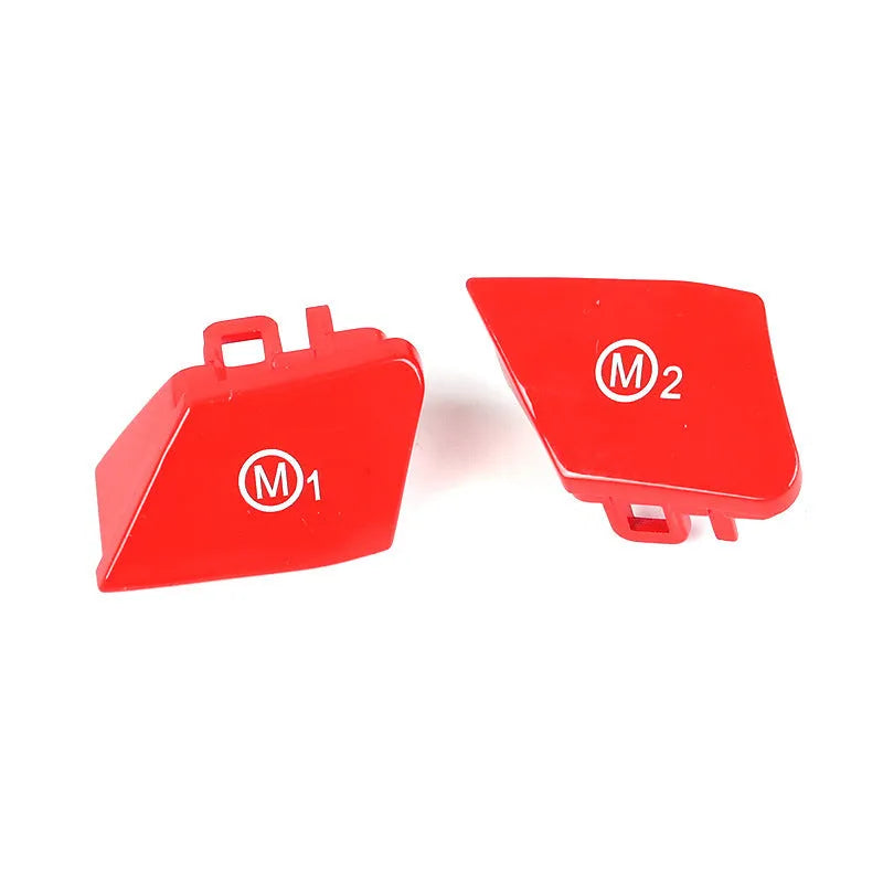 Pair of red and blue BMW M1 M2 steering wheel mode buttons on a dark background.