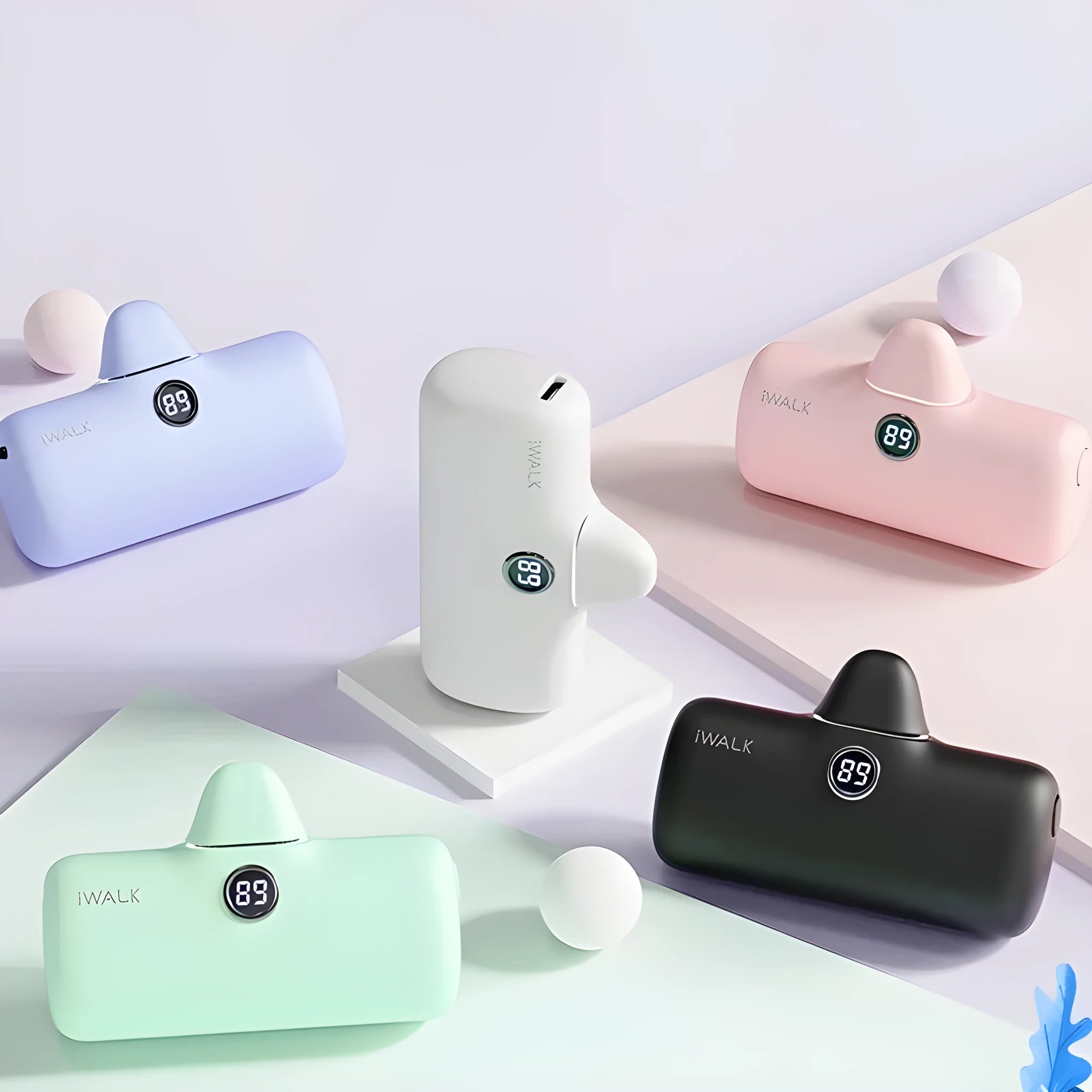 Compact white lipstick-shaped power bank with a digital screen, shown next to a smartphone on its wireless charging pad.