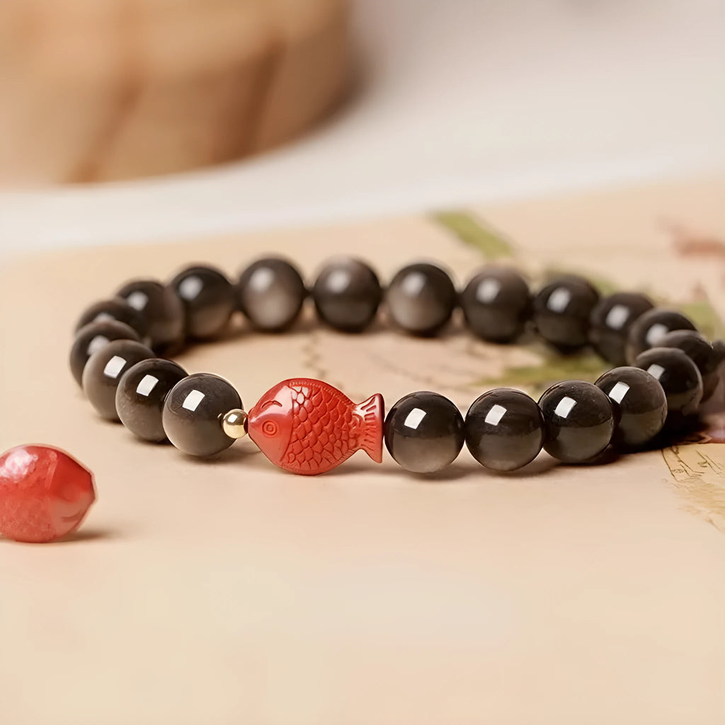 Natural black obsidian round bead bracelet with red cinnabar fungus decorative elements.