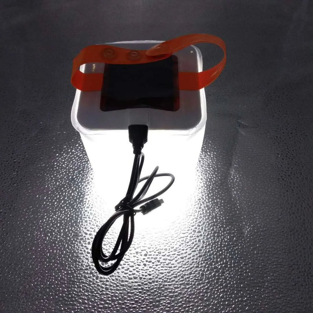 White solar inflatable waterproof camping LED lantern with handle, collapsed flat on a table