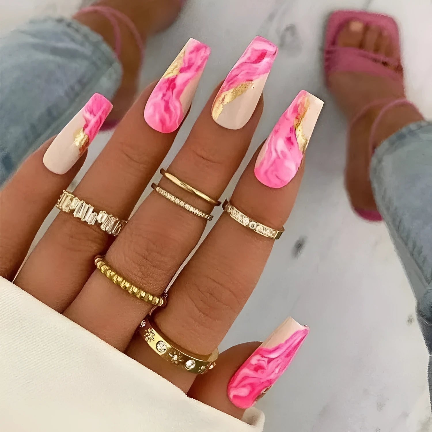 Set of pink press-on artificial nails with rose pattern, shown next to a bottle of nail glue.