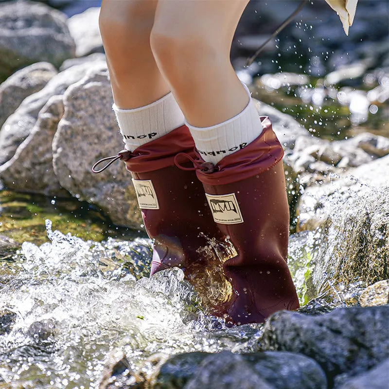 A pair of solid-colour high-tube PVC rain boots with a low heel on a plain background.
