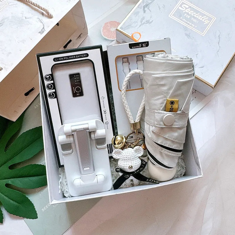 Metal business gift set with bracket, keychain, umbrella, cup, and data cable on a neutral background