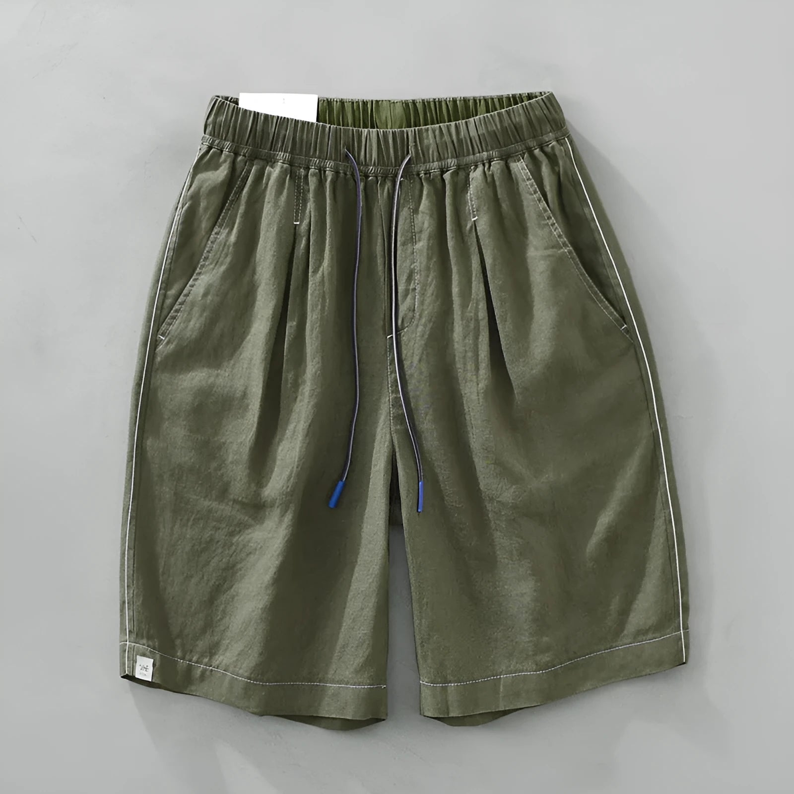 Men's loose fit linen shorts in green on a neutral background