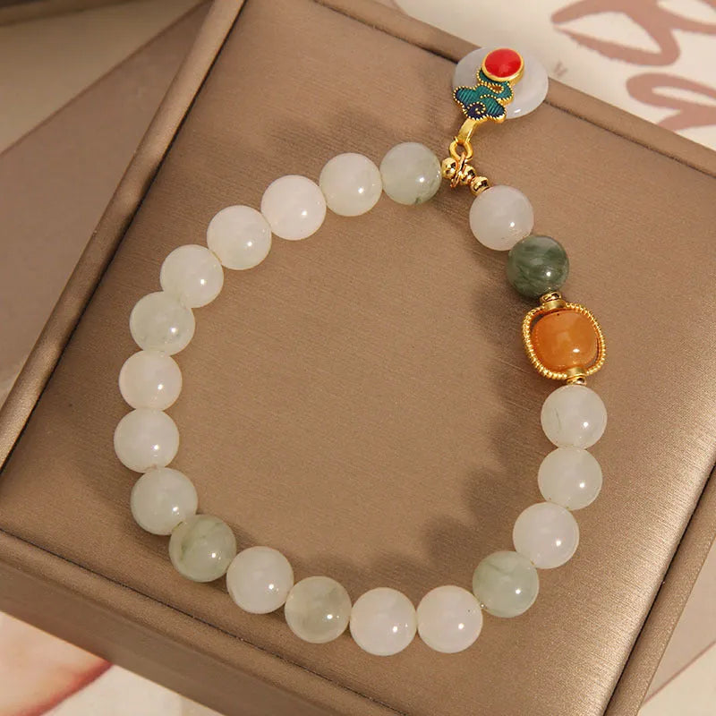 Close-up of a women's ice jade bracelet with carved Xiangyun design, pearl accents, and a jade sliding buckle.