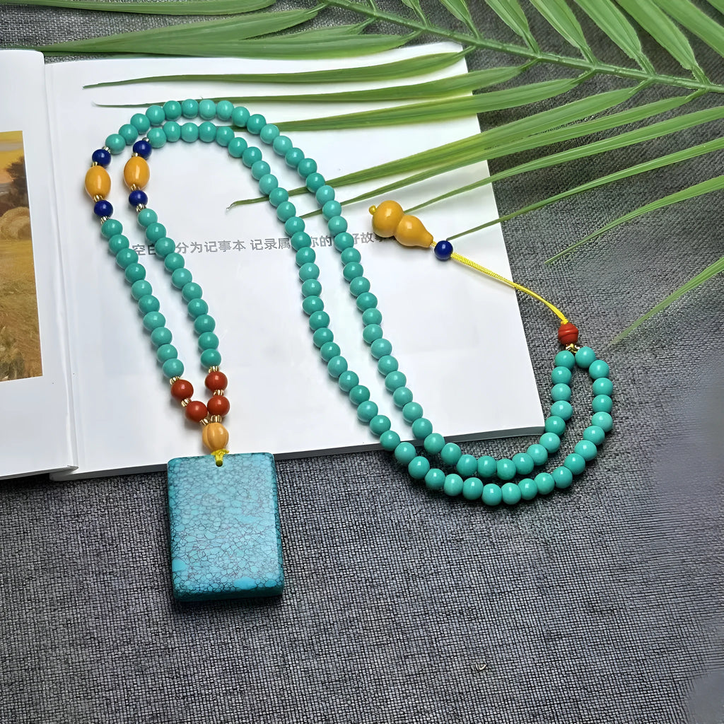 Close-up of a hand-woven turquoise mesh flower pendant on a ball bead necklace, adjustable from 71cm to 80cm.